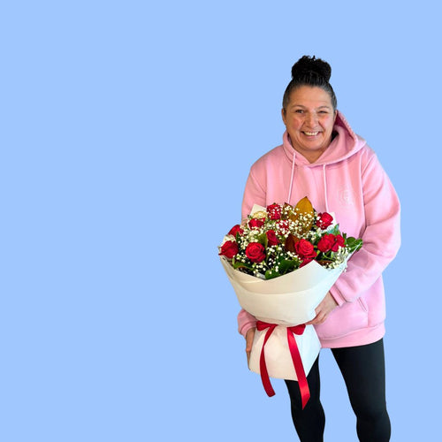 Laura King holding 12 red roses bouquet wrapped in white with red stain bow. in a 360 degree round style. In a white water box, Rangiora florist