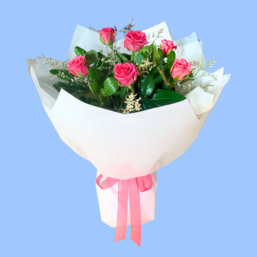 Half dozen pink roses in a white wrapped bouquet in a 360 degree round style. Pink bow.