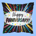 A square black pillow with a scalloped edge, featuring a white central oval that reads 'Happy Anniversary!' in black and rainbow-colored lettering. Radiating from the center are multicolored confetti and streaks on a light blue background.