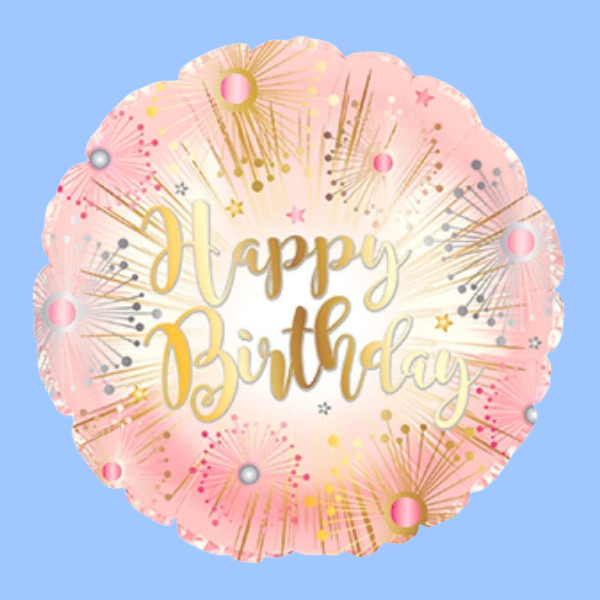 A round foil balloon with scalloped edges, featuring a pink and gold fireworks design with the words 'Happy Birthday' in gold script, set against a solid light blue background.