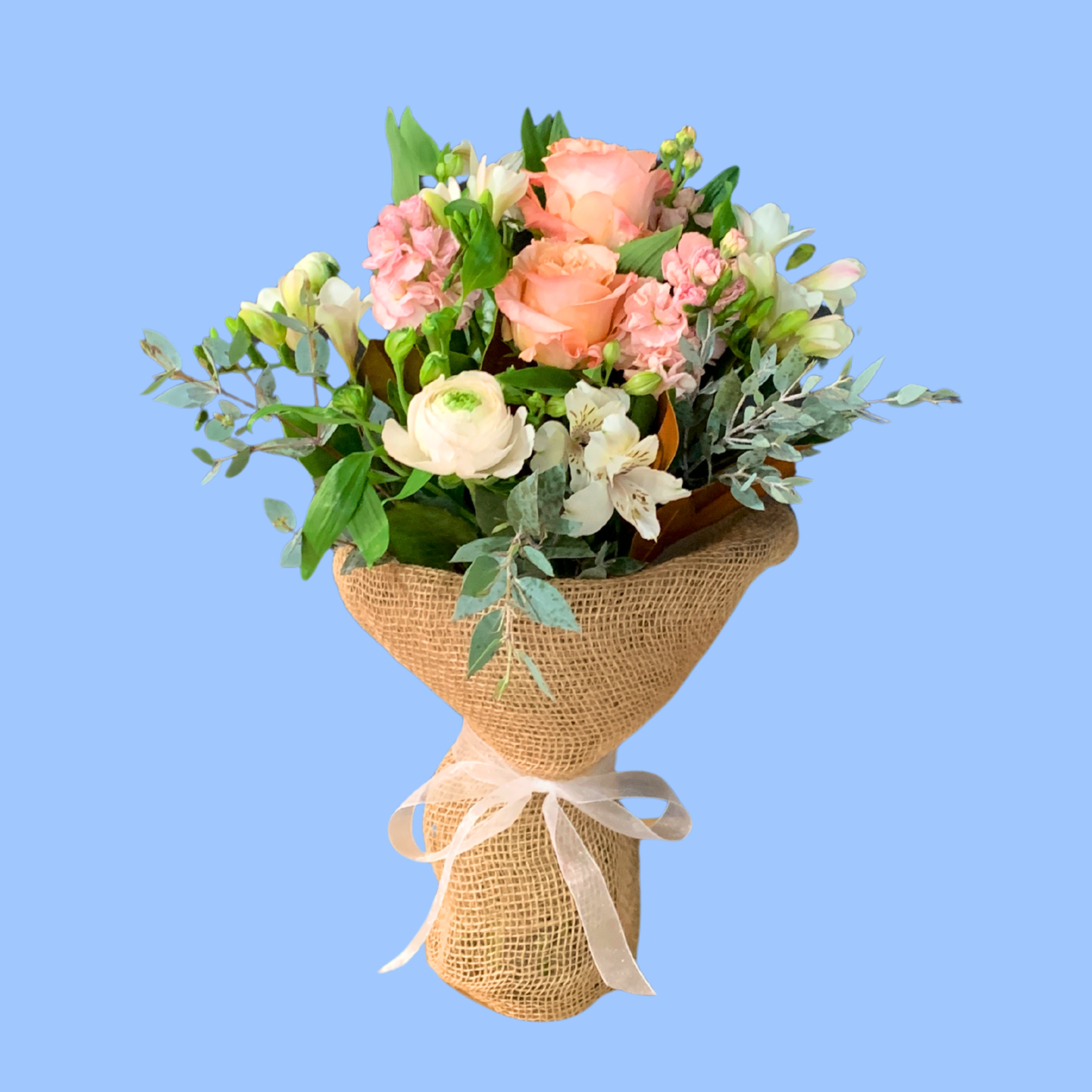 bohemian looking bouquet of crisp pastel flowers in a vase wrapped in brown hessian with a white ribbon.