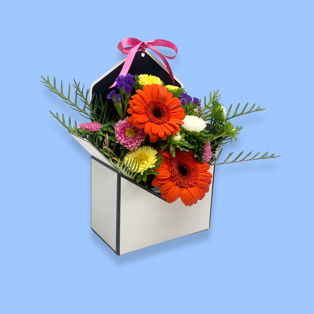 Bright mixed Floral arrangement in an envelope shaped box with a pink bow 