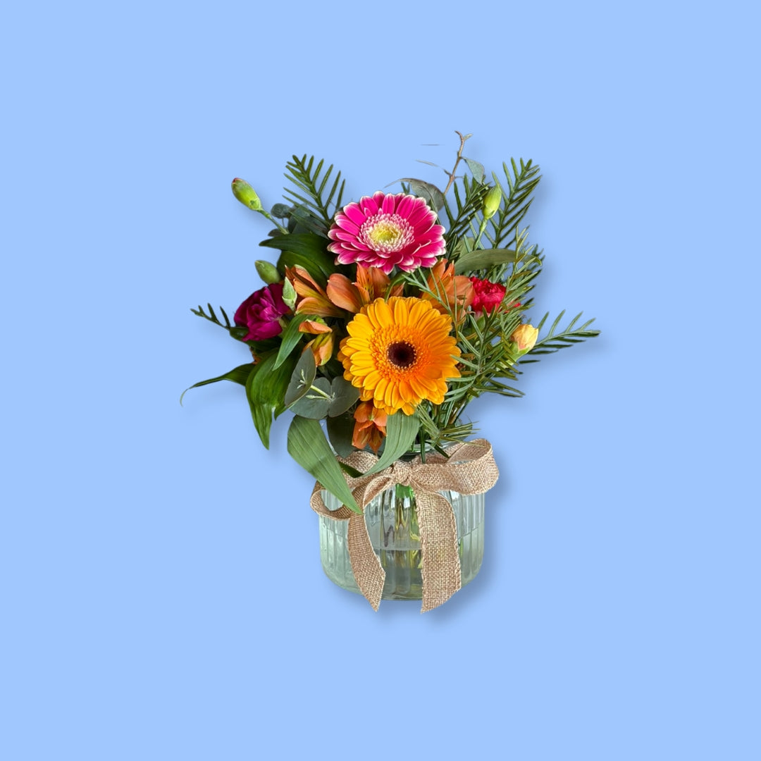 Hand-tied bright seasonal posy in a vase