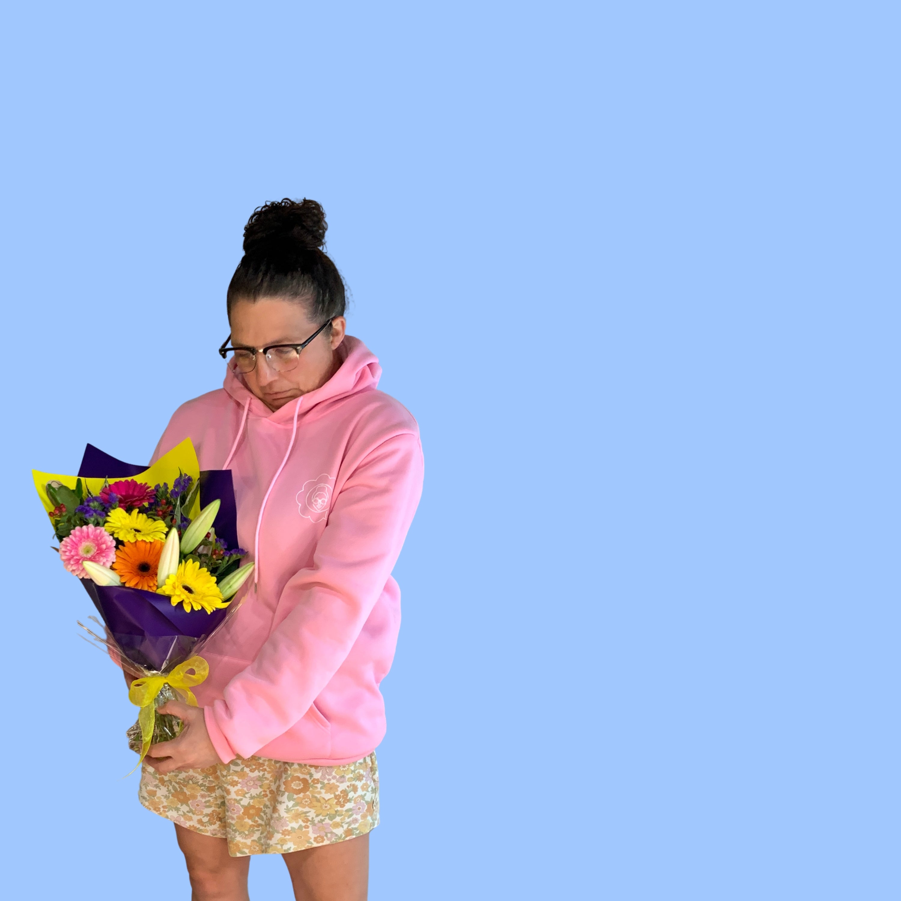 Laura king holding a bouquet of colourful flowers wrapped in purple and yellow.