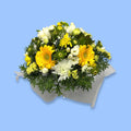 Box arrangement of crisp bold yellow and white flowers with greenery against white tissue.