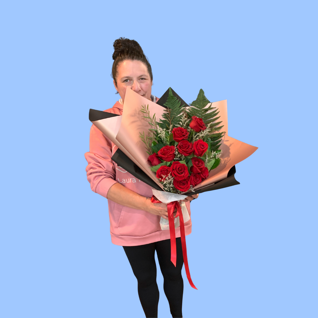 Laura King holding Elegant dozen red roses bouquet in black and rose gold wrap