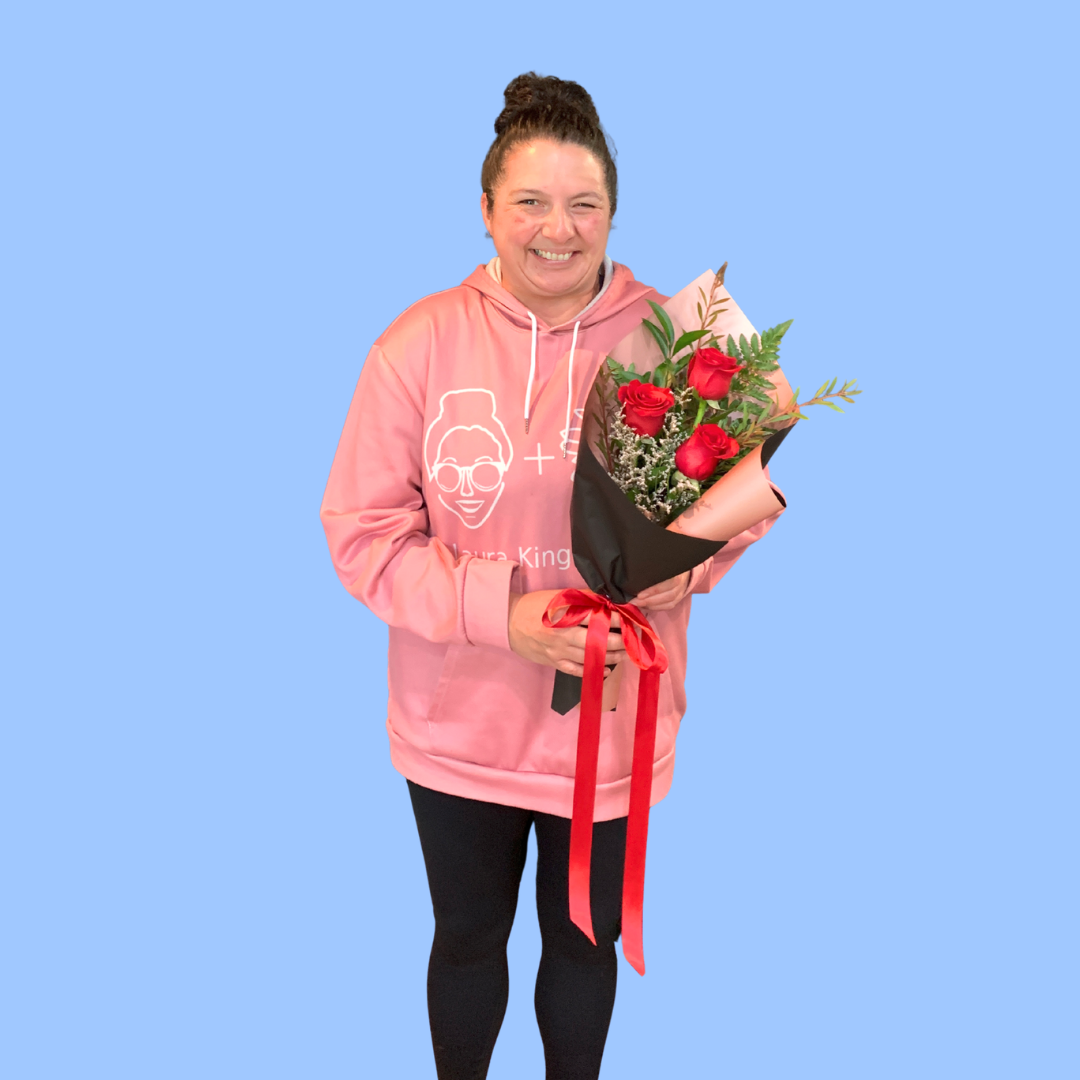 Laura King holding Elegant 3 red rose bouquet, wrapped in black and rose gold, with trailing satin ribbon