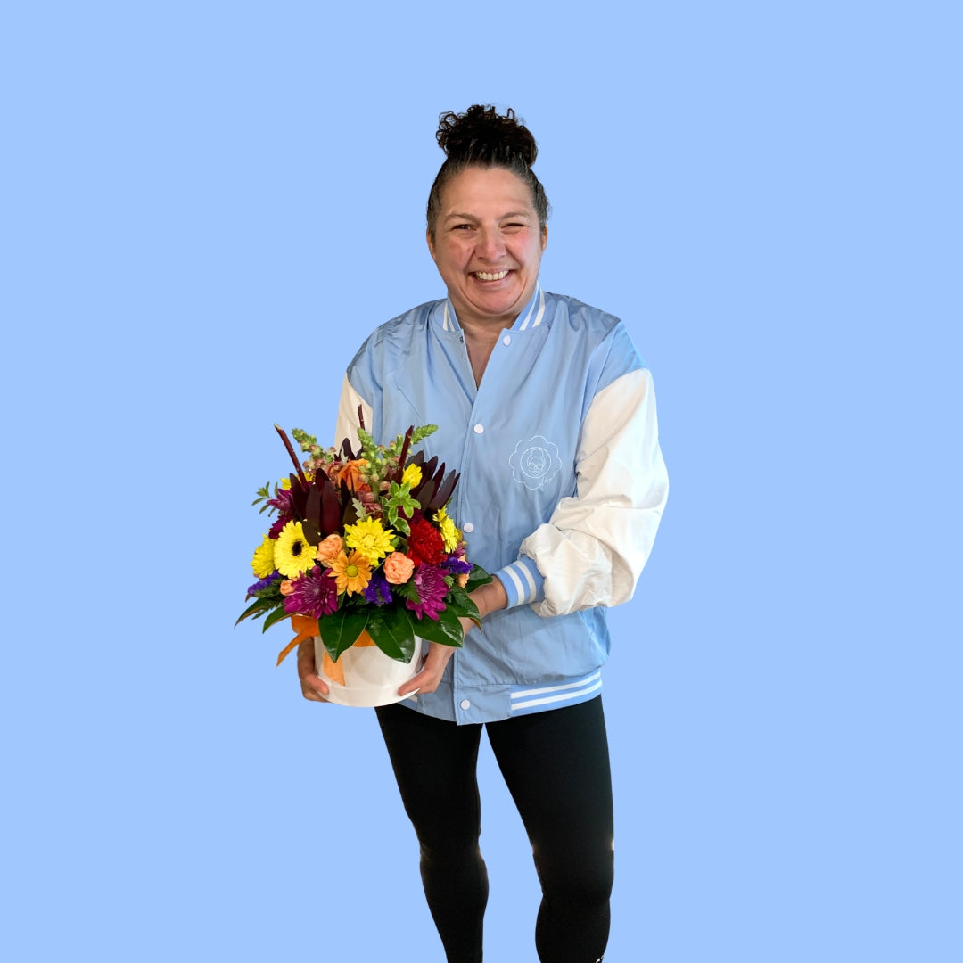 laura king holding a Large Bold bright flower arrangement in cylindrical white hat box
