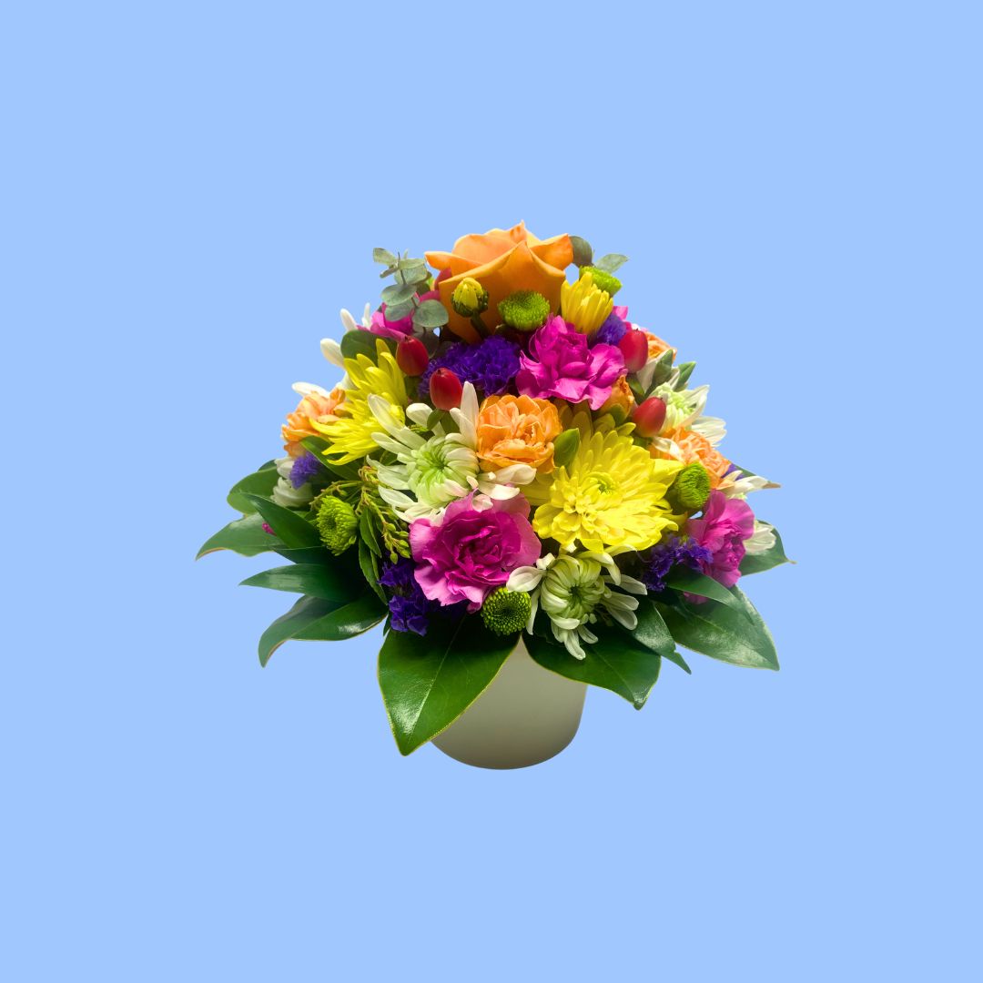 colorful flower arrangement in 360 degrees round viewing style in a small white cylindrical ceramic pot.