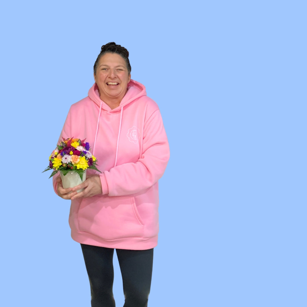 Laura king holding a colorful flower arrangement in 360 degrees round viewing style in a small white cylindrical ceramic pot.