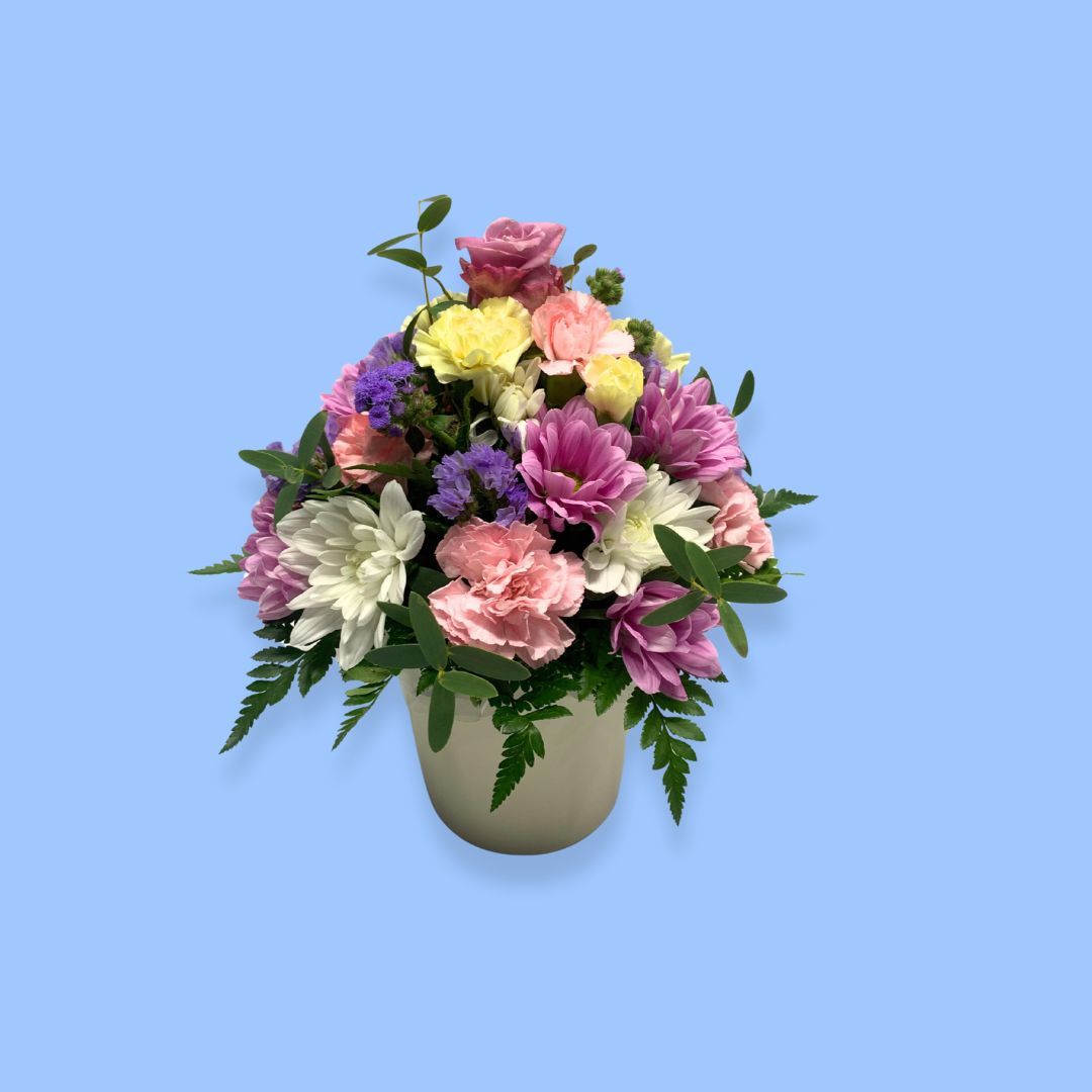 pastels flower arrangement in 360 degrees round viewing style in a small white cylindrical ceramic pot.