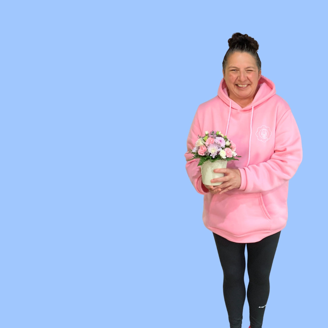 Laura king holding a pastels flower arrangement in 360 degrees round viewing style in a small white cylindrical ceramic pot.