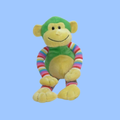 A plush smiling monkey toy with a green head and torso, yellow face, belly and limbs, and rainbow-striped arms and legs, centered on a light blue background.