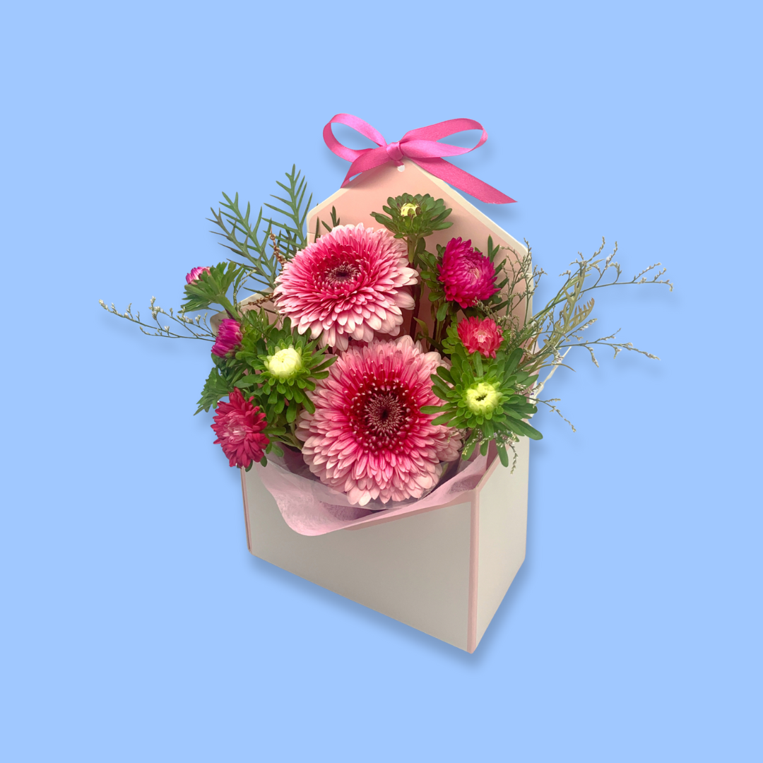 Pink Floral arrangement in an envelope shaped box with pink vilene and a pink bow 