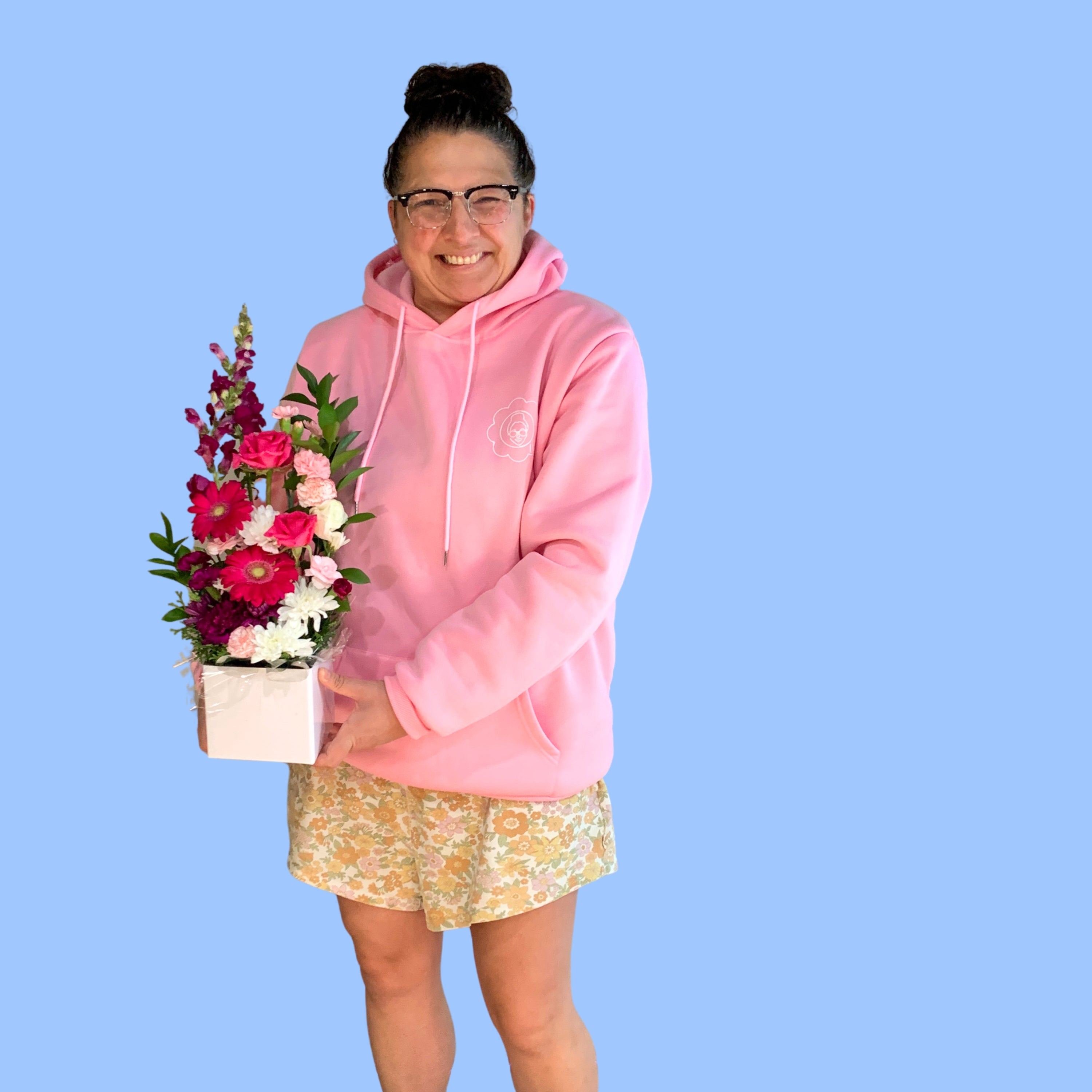 Laura King holding Tall upright arrangement of pink and white flowers in a white box