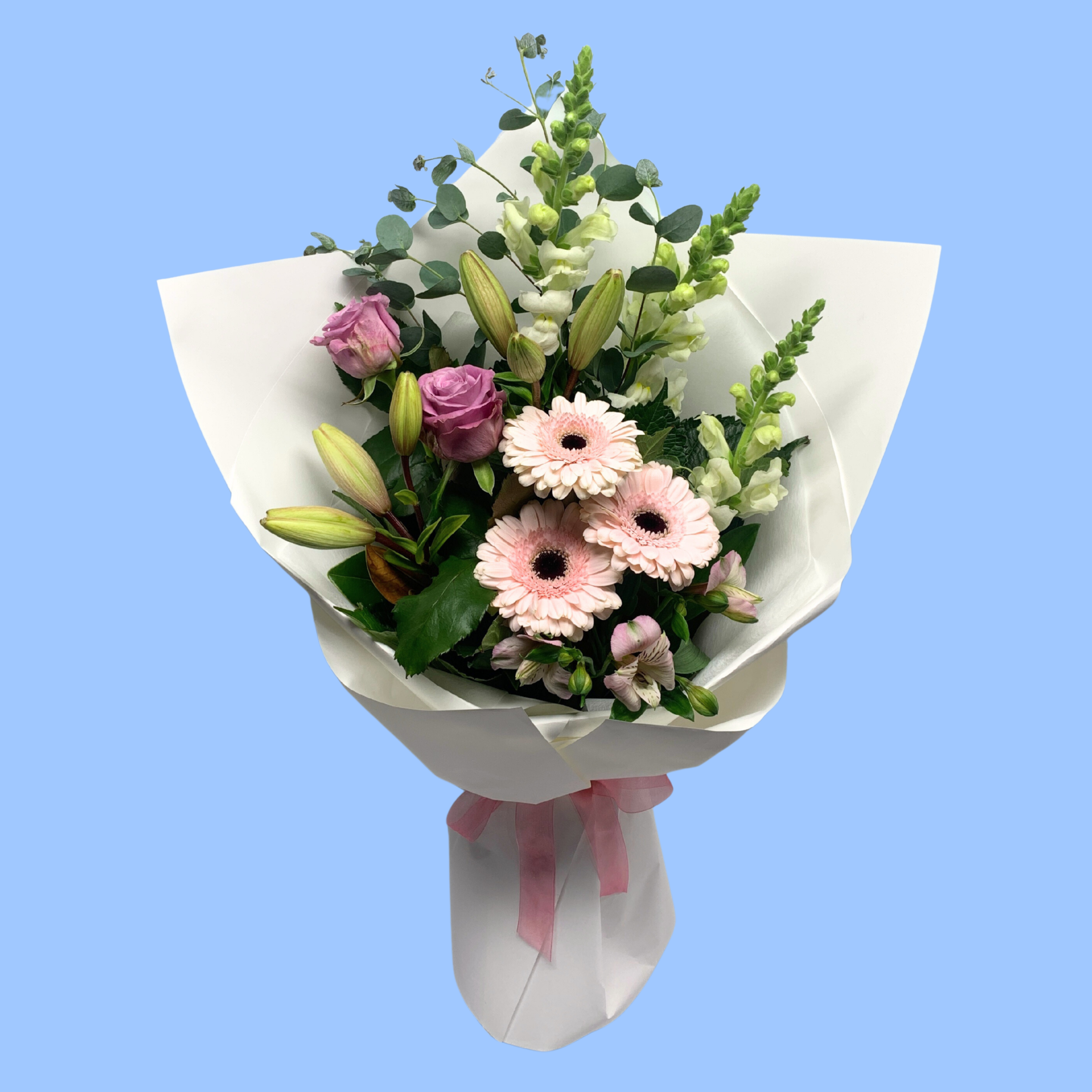 soft pastels coloured flowers in a bouquet wrapped in white with light pink bow