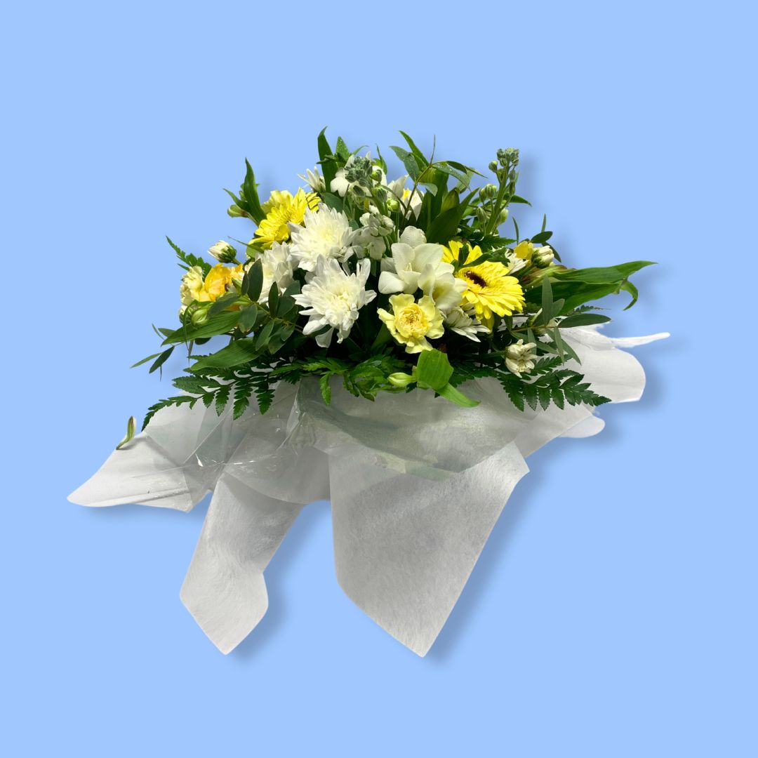 arrangement of flowers with white and yellow flowers against white tissue 
