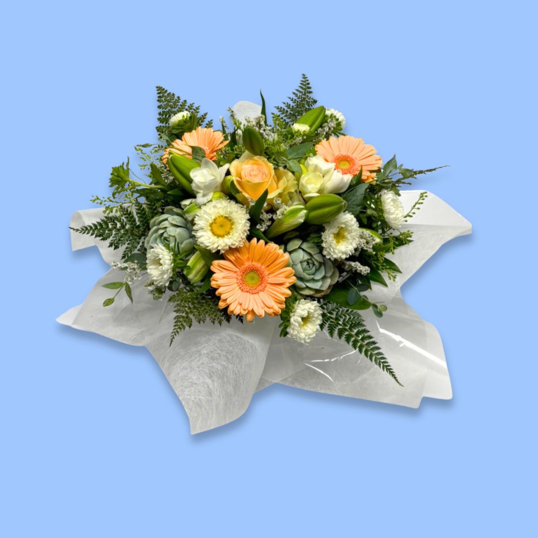 arrangement of apricot and white flowers against greenery and white tissue.