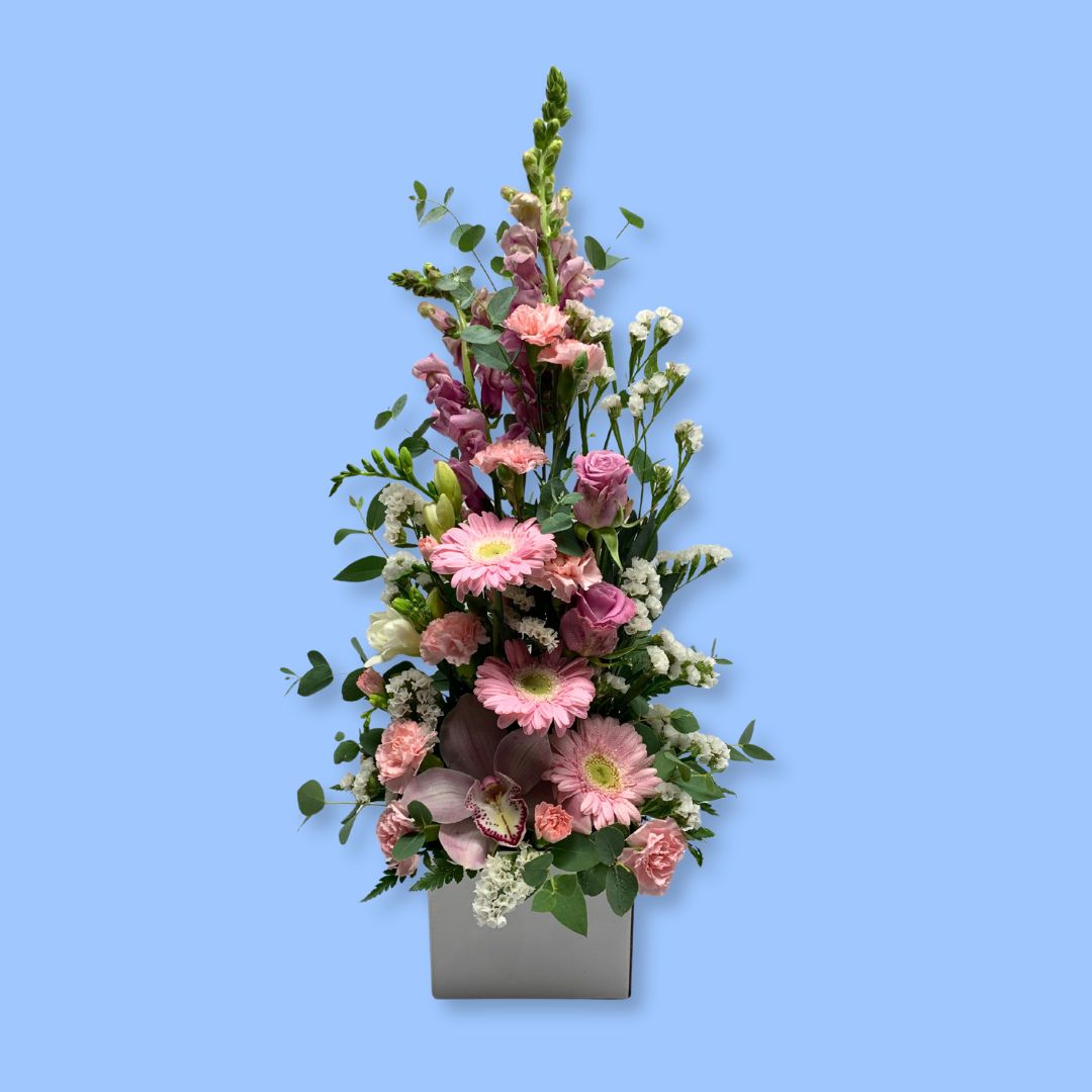 Tall upright arrangement of pastels coloured flowers in a white box