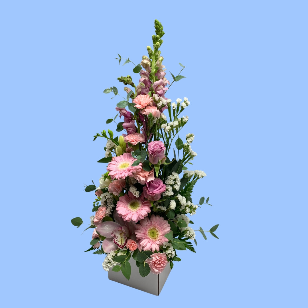angled view of Tall upright arrangement of pastels coloured flowers in a white box