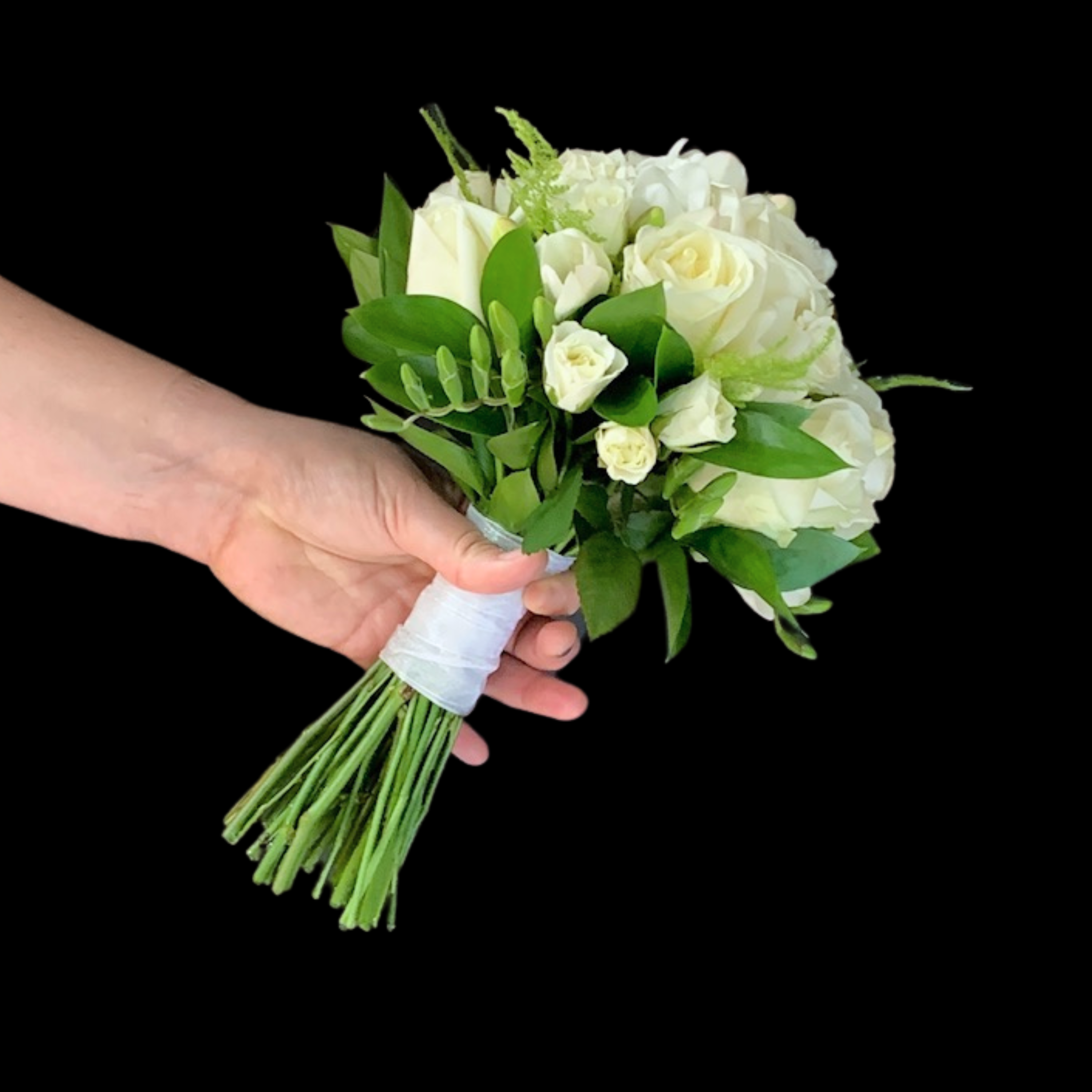 a hand holding a traditional tightly arranged round wedding bouquet of cream and white flowers. ribbon wrapped stems.
