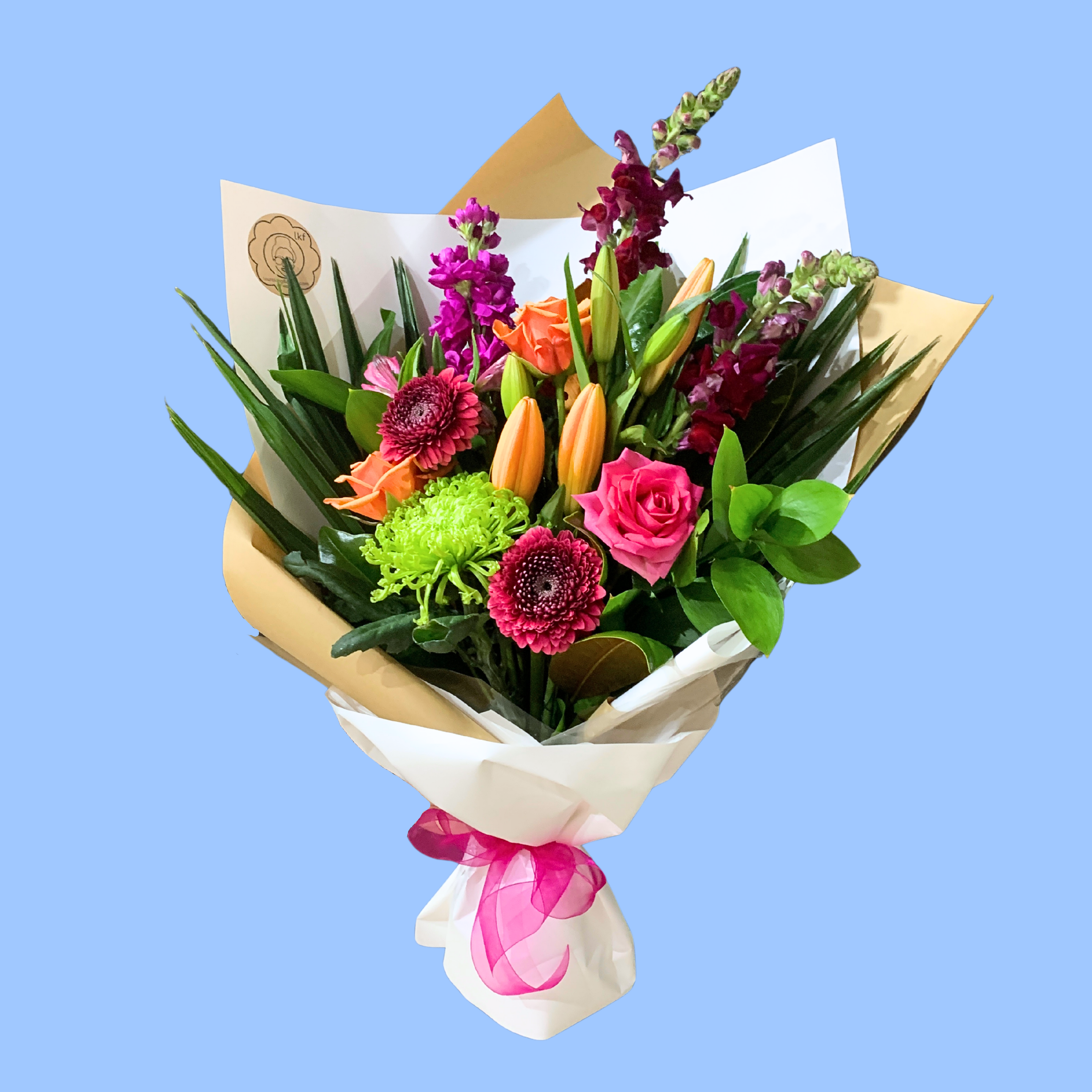Mixed Bouquet of vibrant coloured flowers wrapped in craft and white with vibrant pink bow.