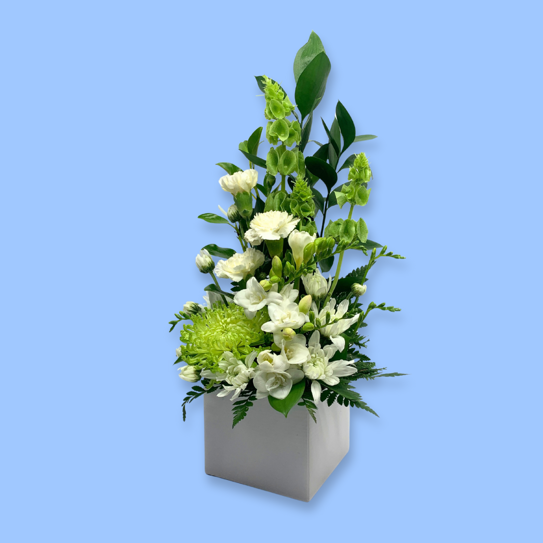 Upright Tall flower arrangement of white and green sympathy coloured flowers in white box.