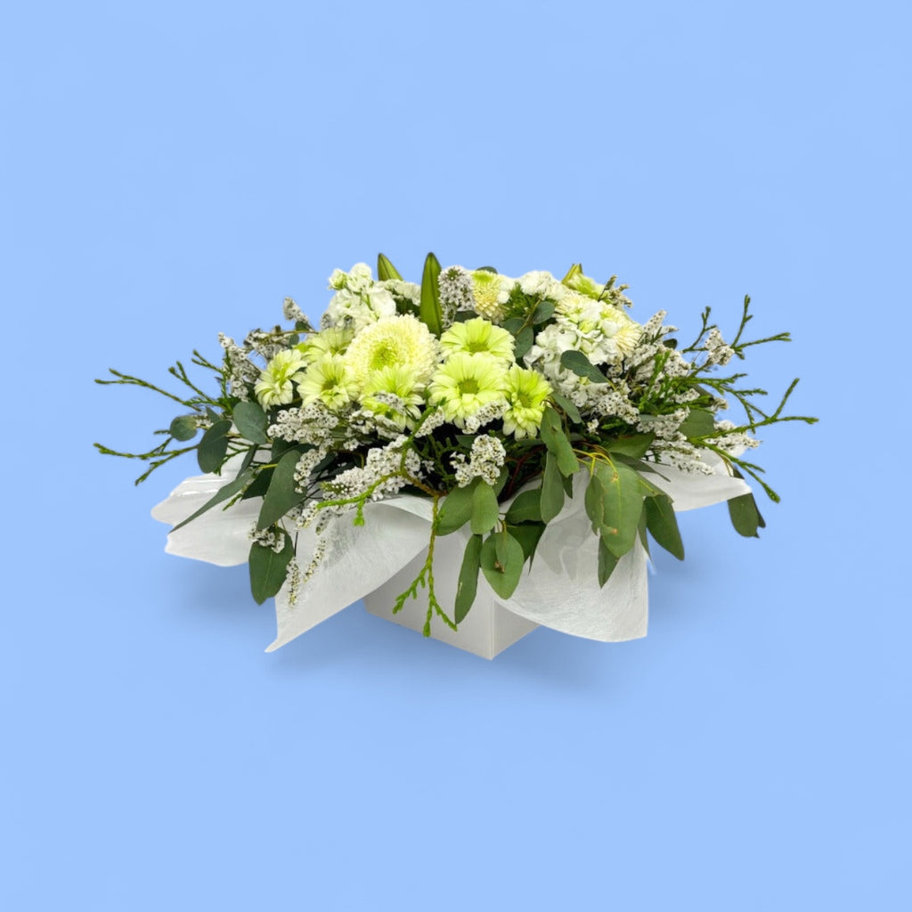Arrangement of lime and white flowers in a white box line with white tissue