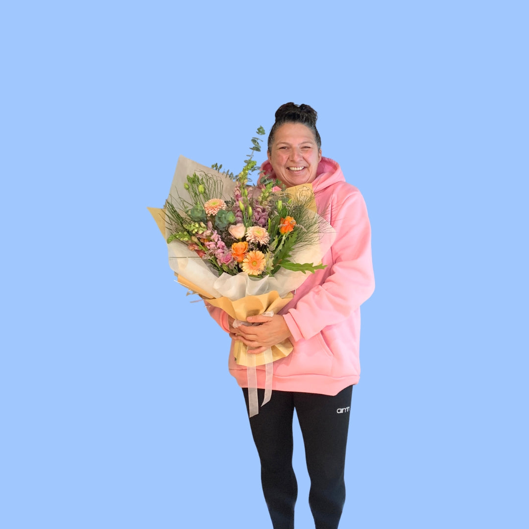 Laura holding Natural wild-style bouquet with seasonal pastel flowers craft wrapped and white vilene.white bow