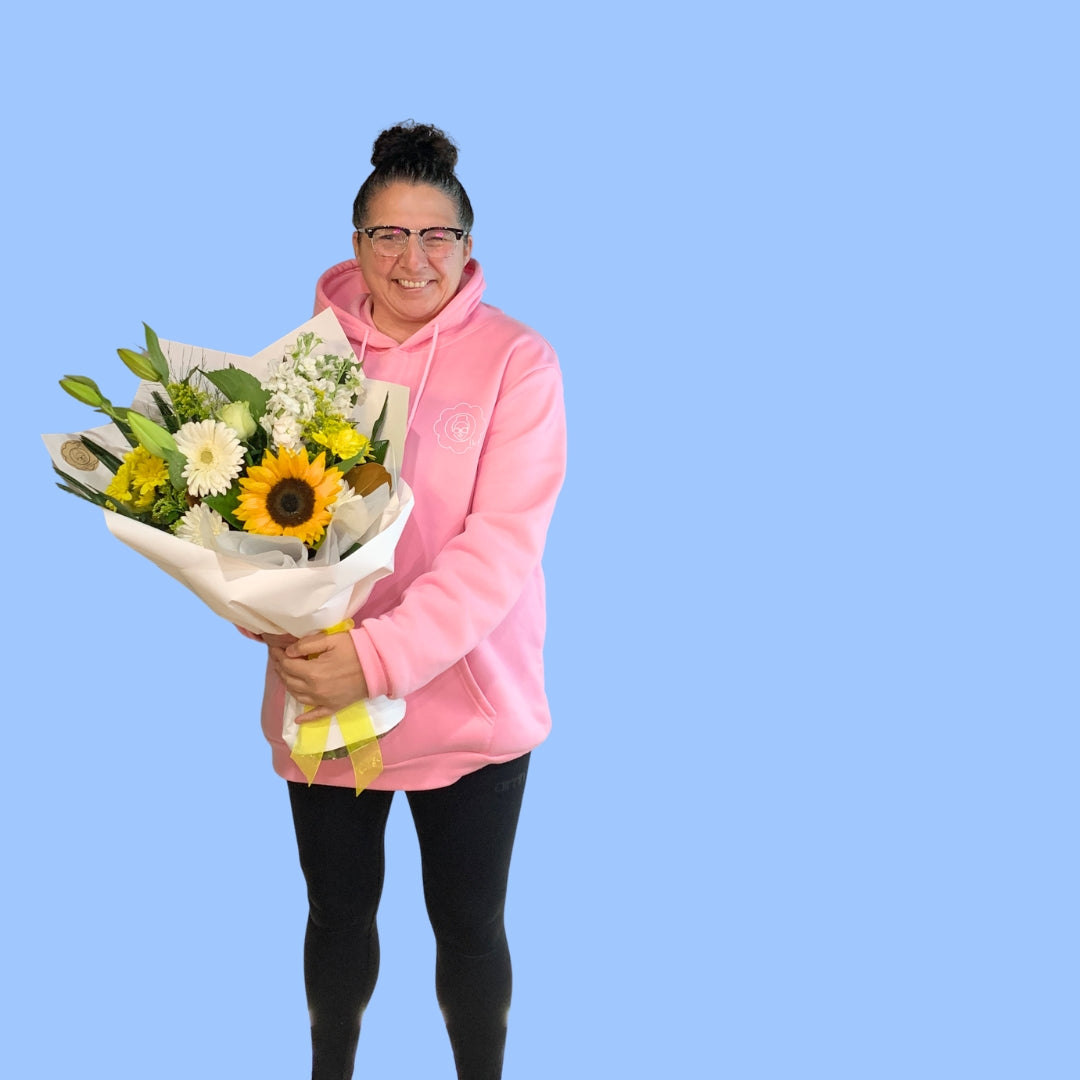 Laura King holding Yellow and white flower bouquet wrapped in white with yellow vilene and bow, popular for gifting and sympathy