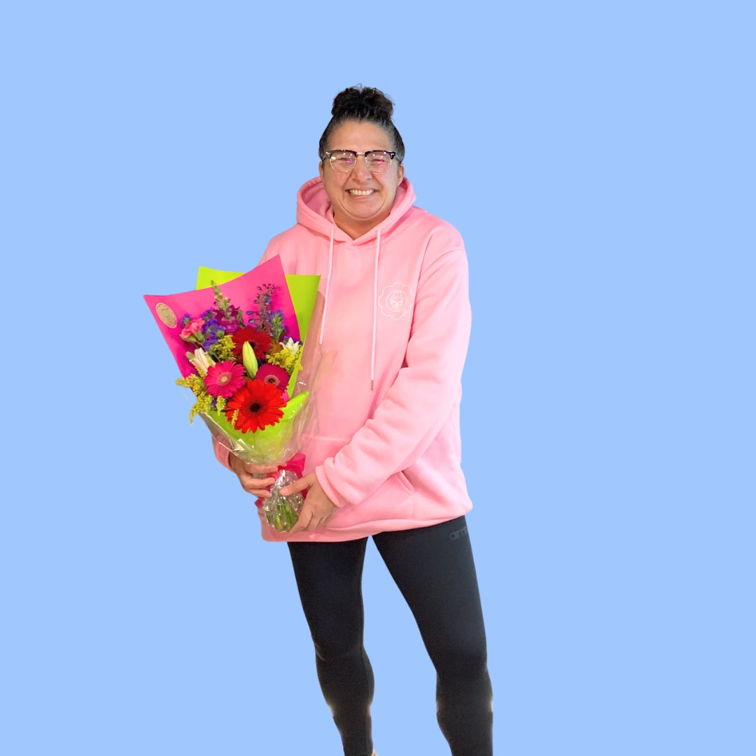 Laura King holding Bouquet of colorful flowers wrapped in pink paper and lime green