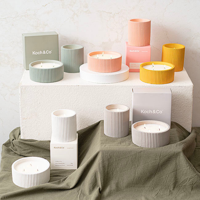 Collection of colorful candles and boxes with 'Koch & Co' branding on a neutral background.